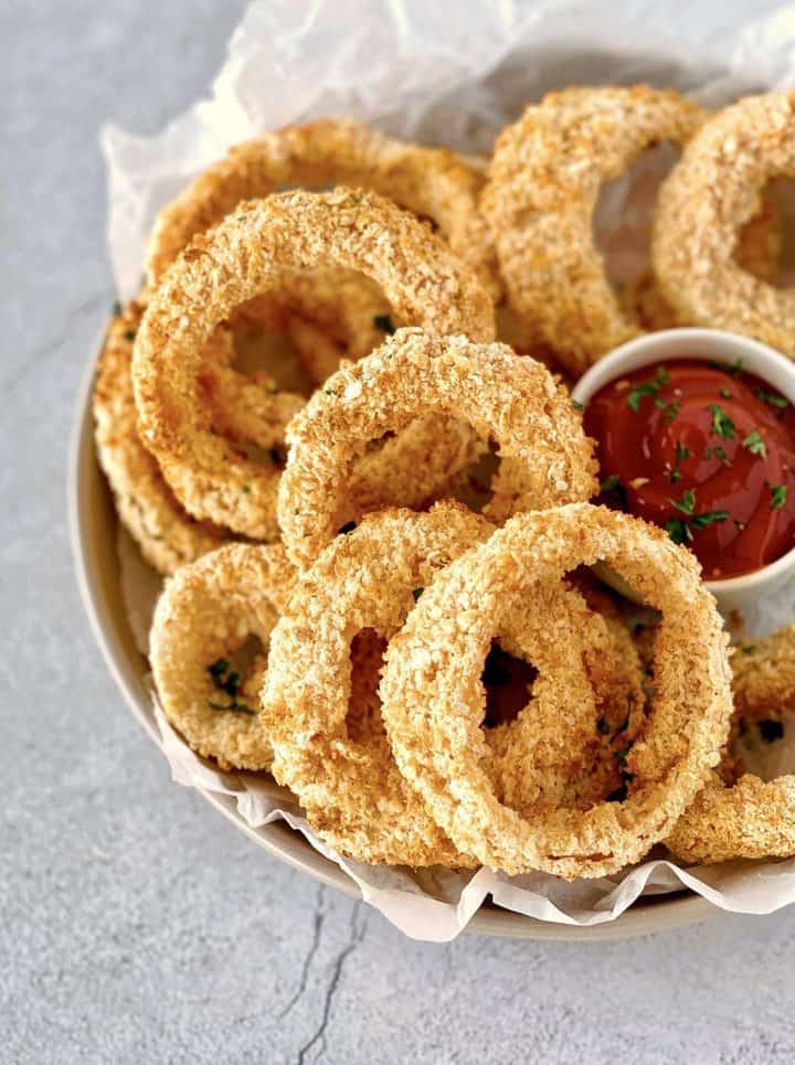 bowl of onion rings next to ketchup 