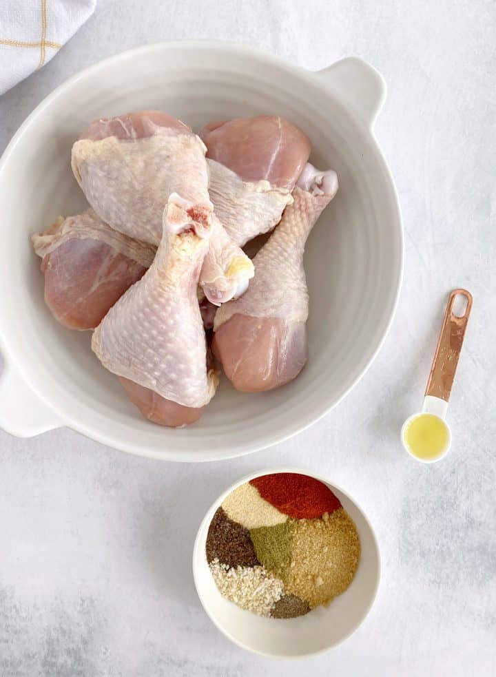 raw chicken in a bowl with seasonings in a bowl