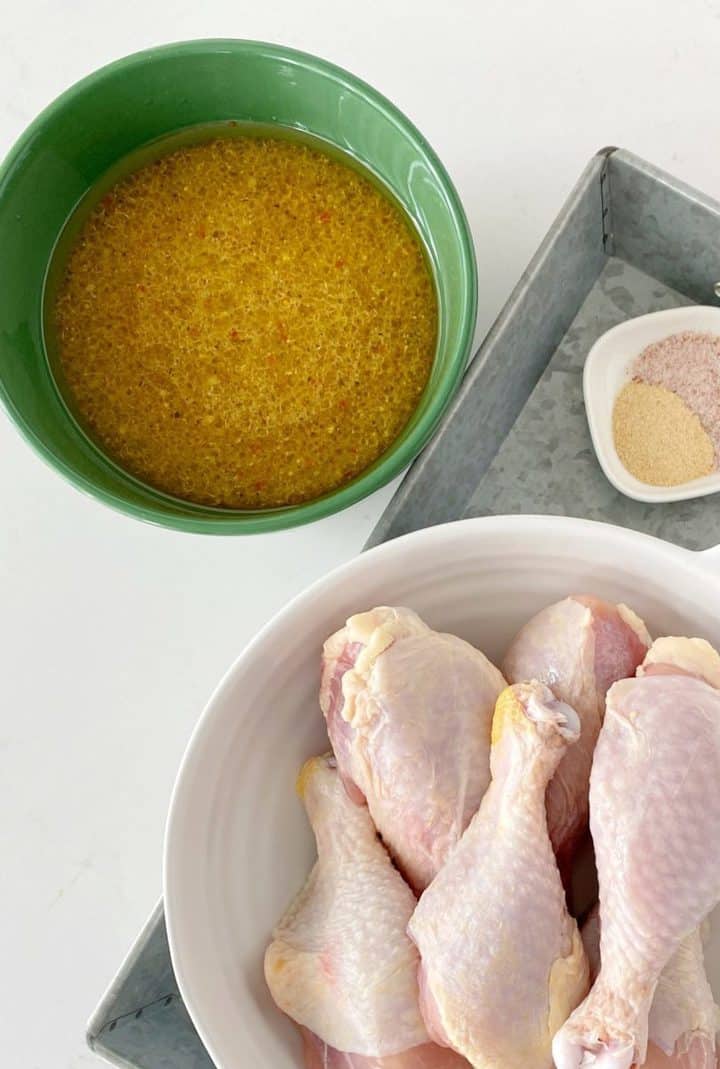bowl of seasoning and dressing next to chicken legs