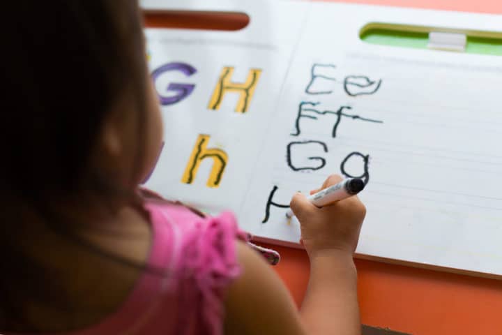 girl tracing letters on a book 