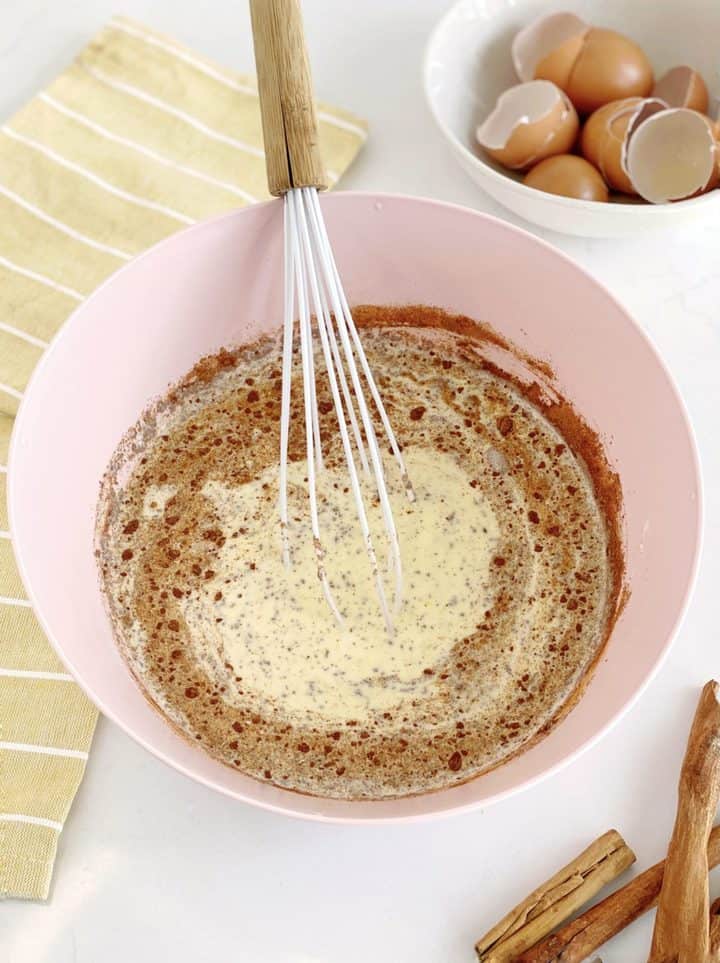 bowl of milk, seasonings and eggs with a whisk inside a bowl