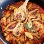 close up of chicken afritada with a wooden spoon