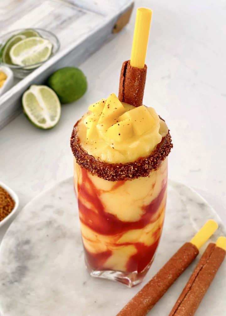 glass of mango shake with angoes and tamarindo straw 