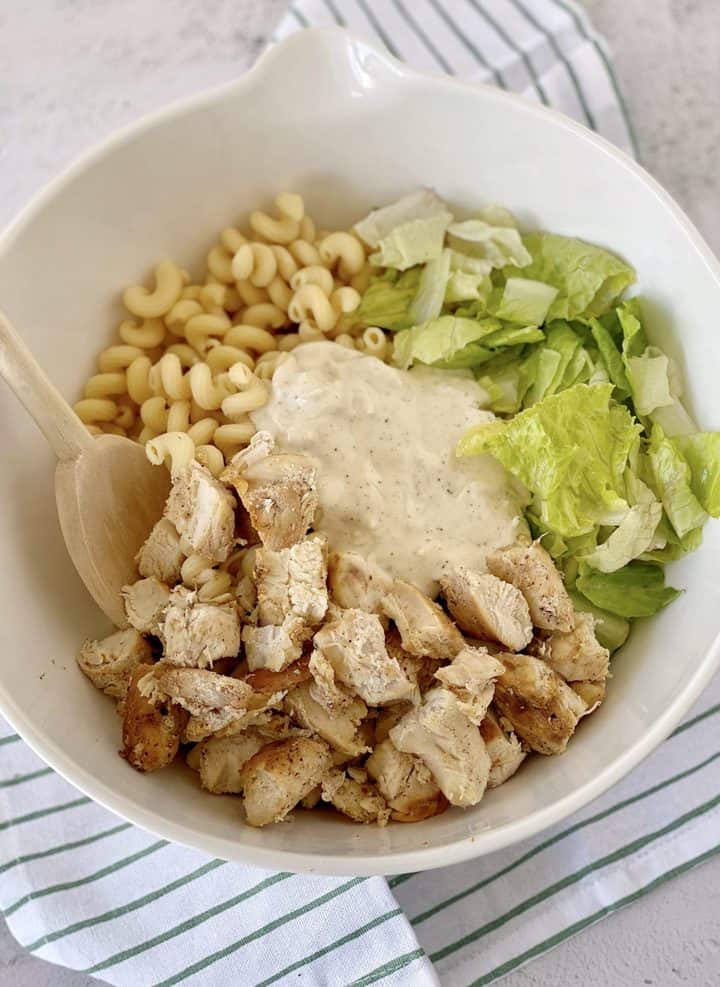 bowl of lettuce, pasta, chicken and dressing