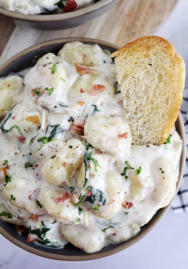 bowl of creamy gnocchi with bread on top 
