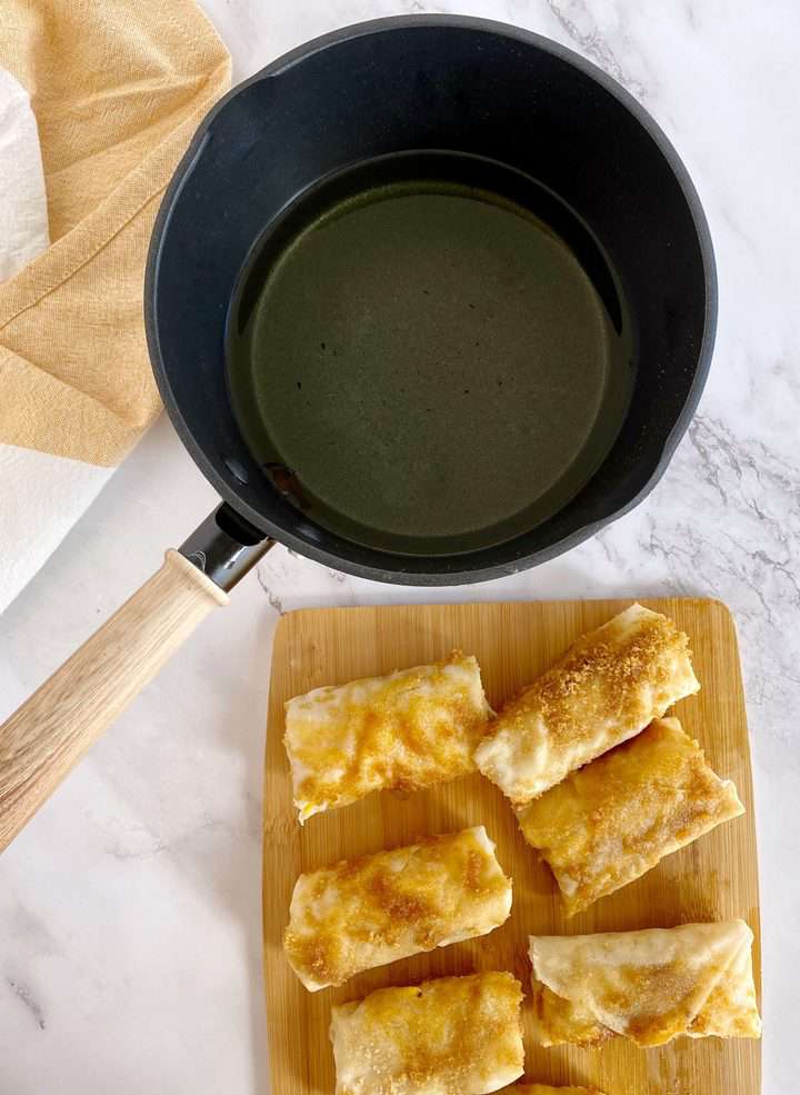 pot of oil with prepared eggrolls on side 