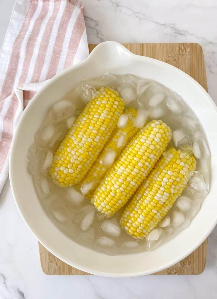 bowl of ice and water with corn