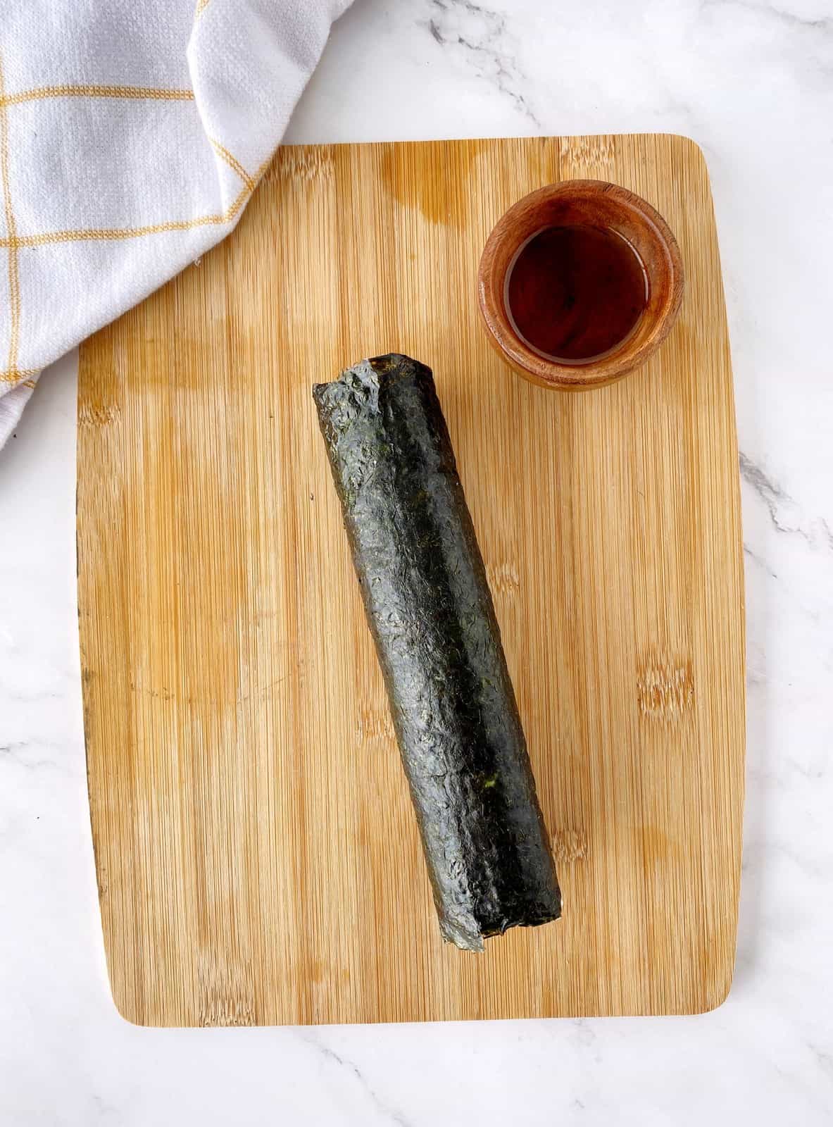 roll of kimbap on a wooden board 