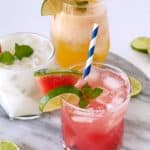 agua fresca glasses garnished with fruit and a straw