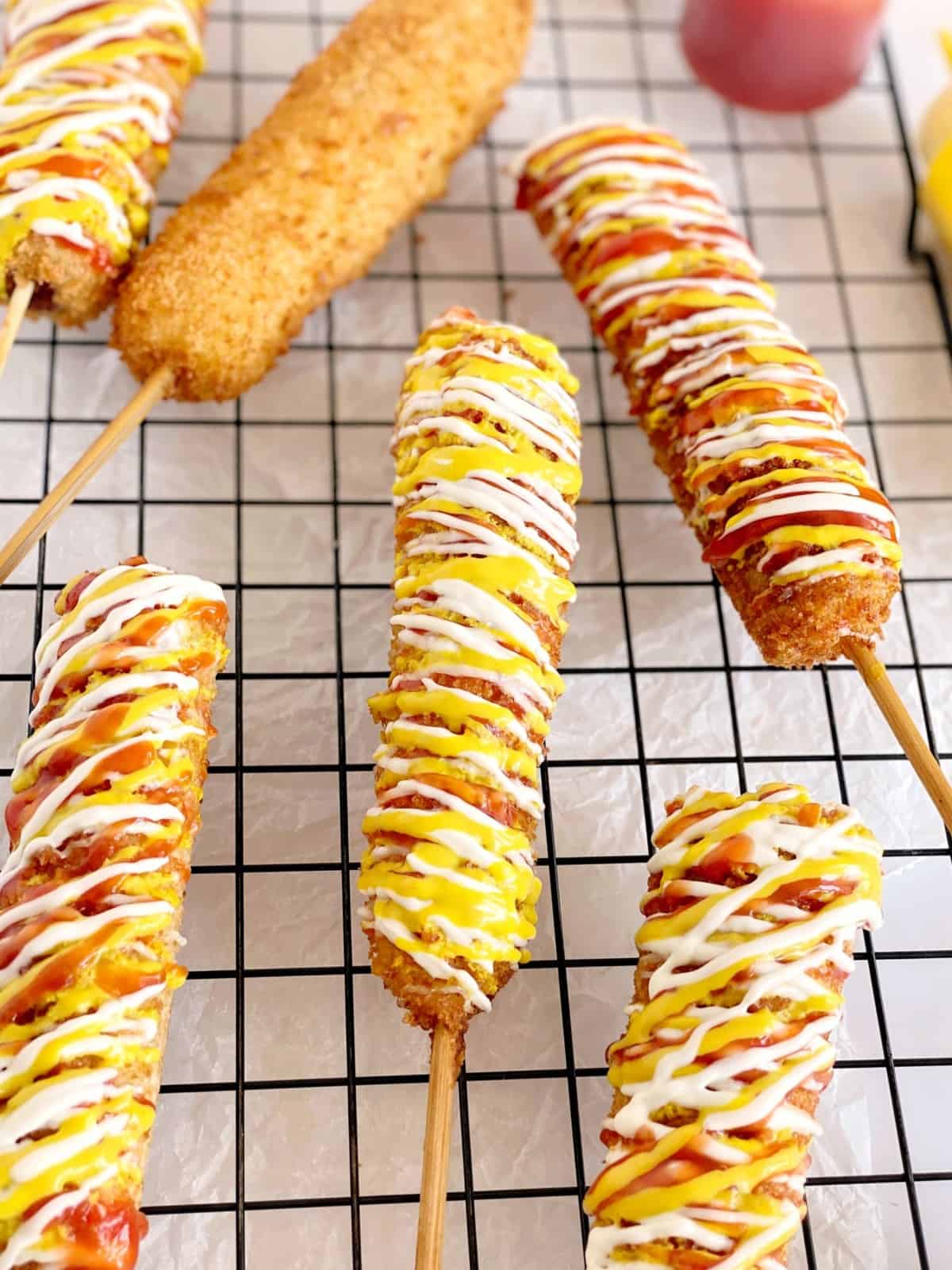 korean corn dogs with mustard and ketchup on a wire rack