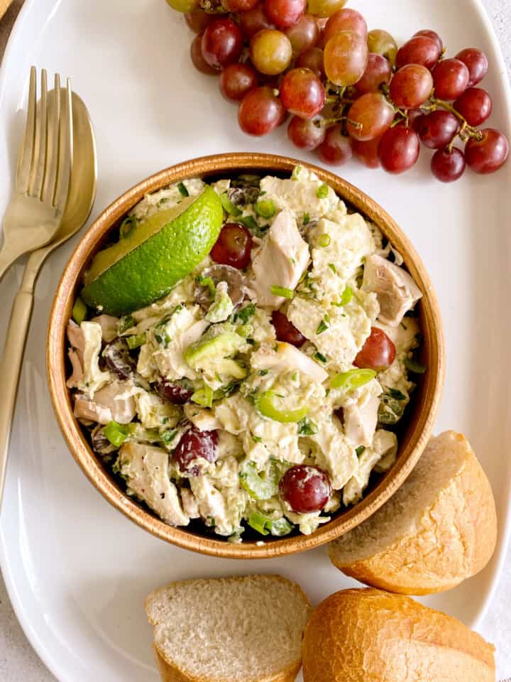 bowl of chicken salad next to grapes