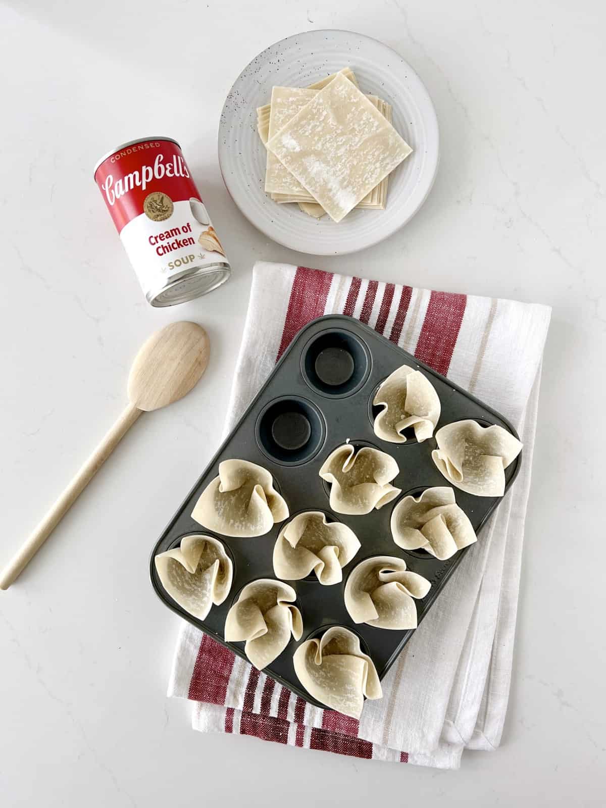 muffin tin with wonton wrappers tucked in each circle next campbells soup and cheese 