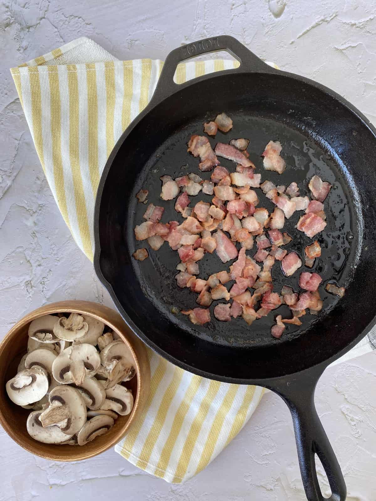 bacon in a skillet next to mushrooms 