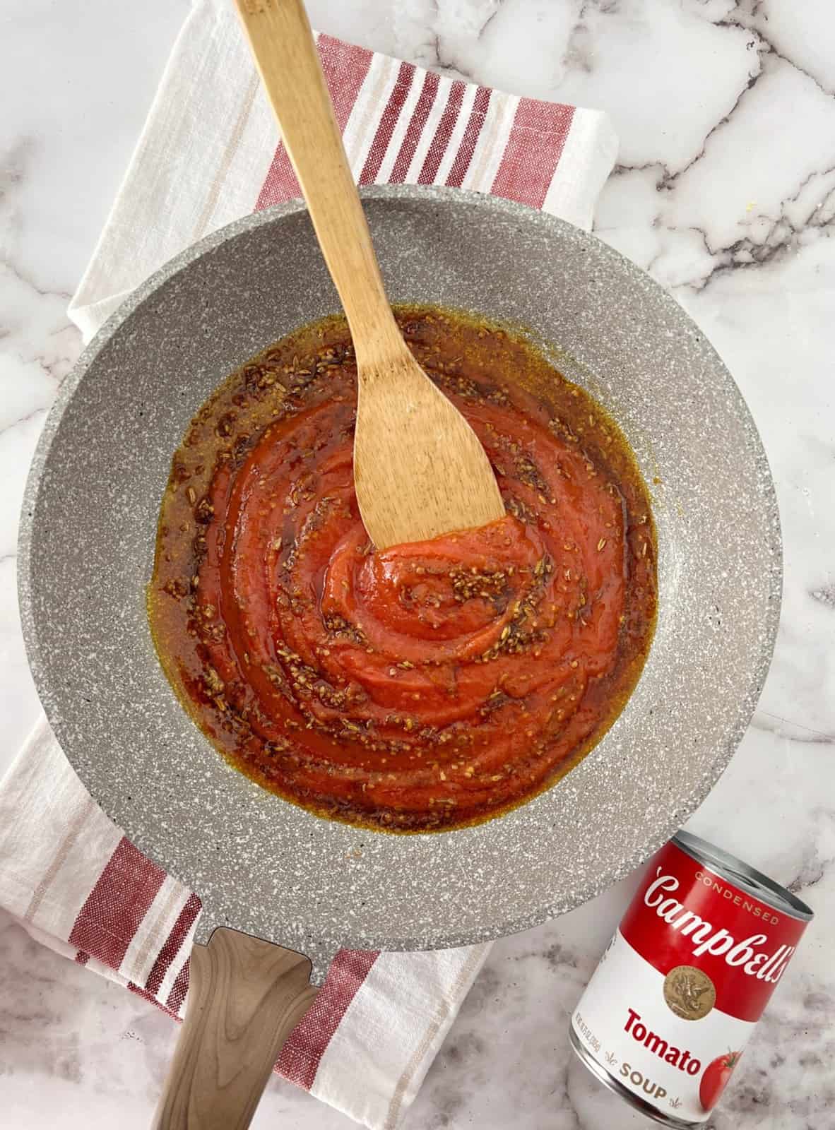 pan of tomato soup with spices and wooden spoon 
