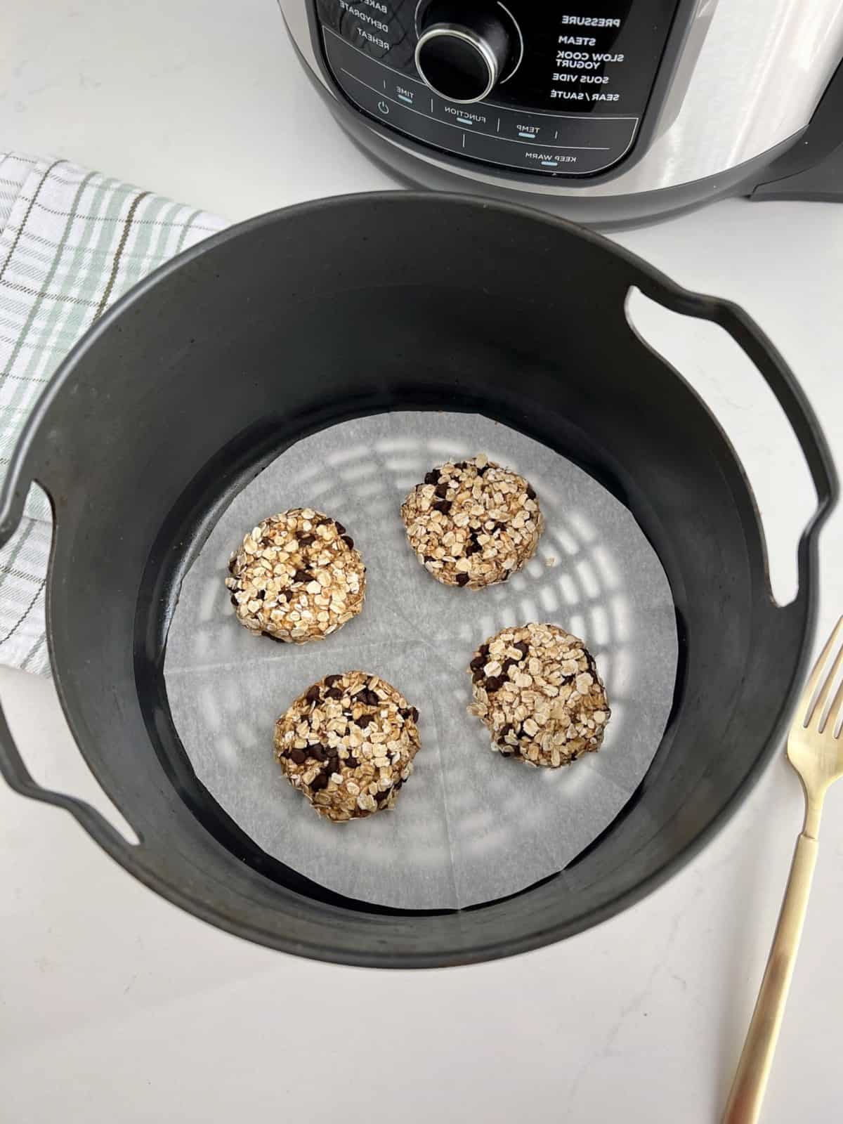 air fryer with parchment paper and cookies on top 