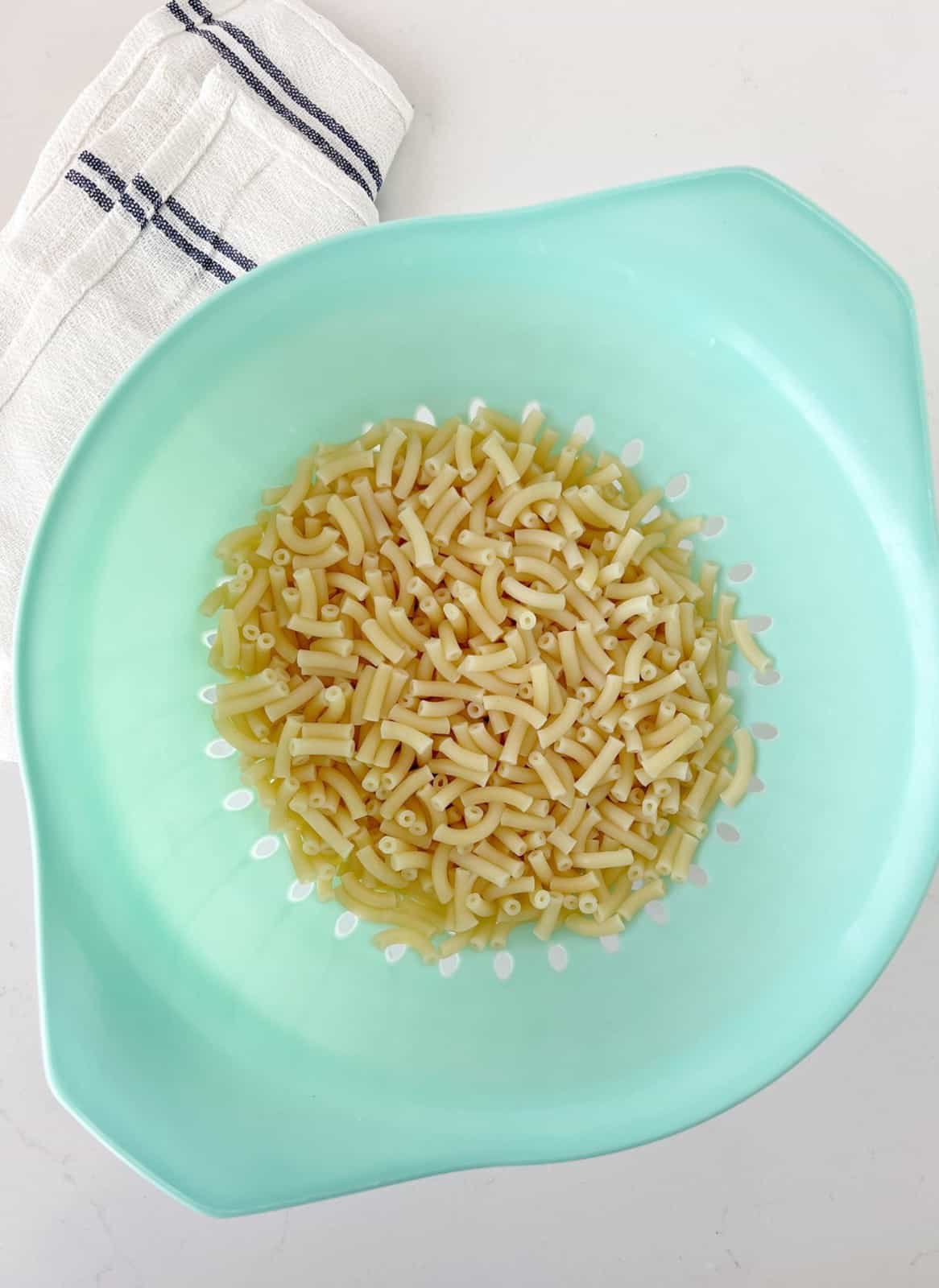green strainer with macaroni pasta 