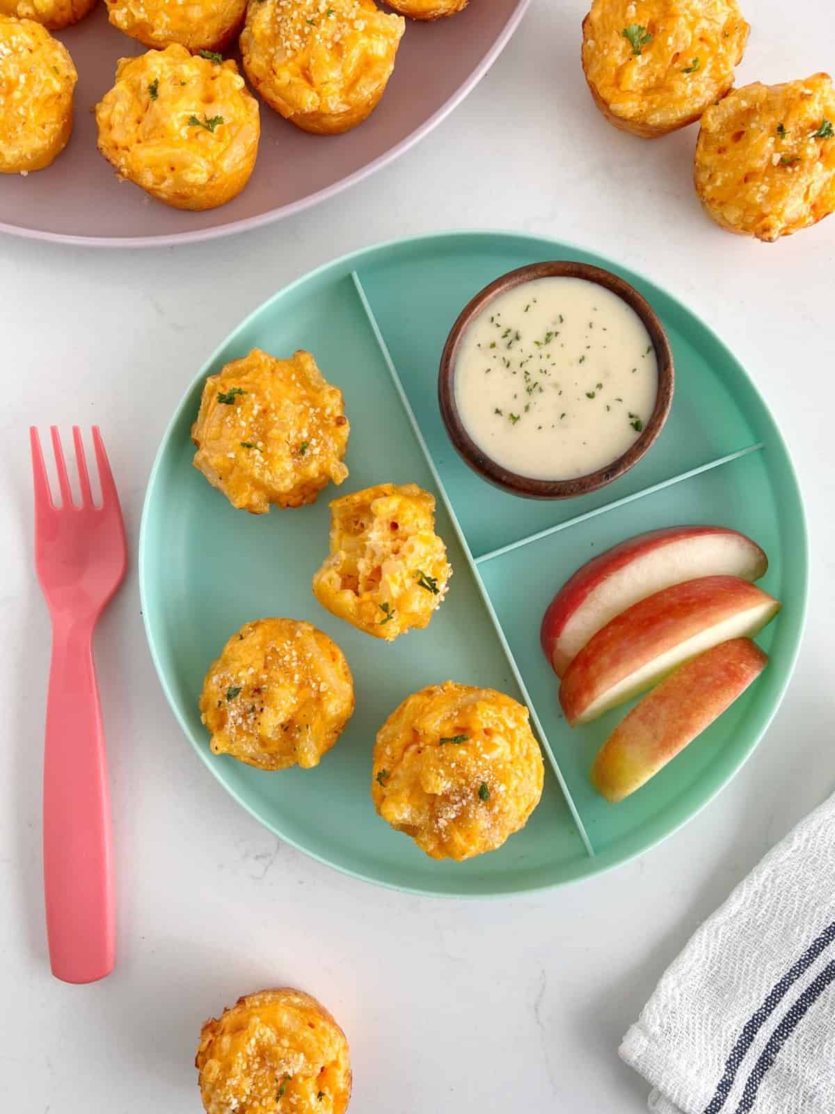 baked mac and cheese bites on a plate next to apples