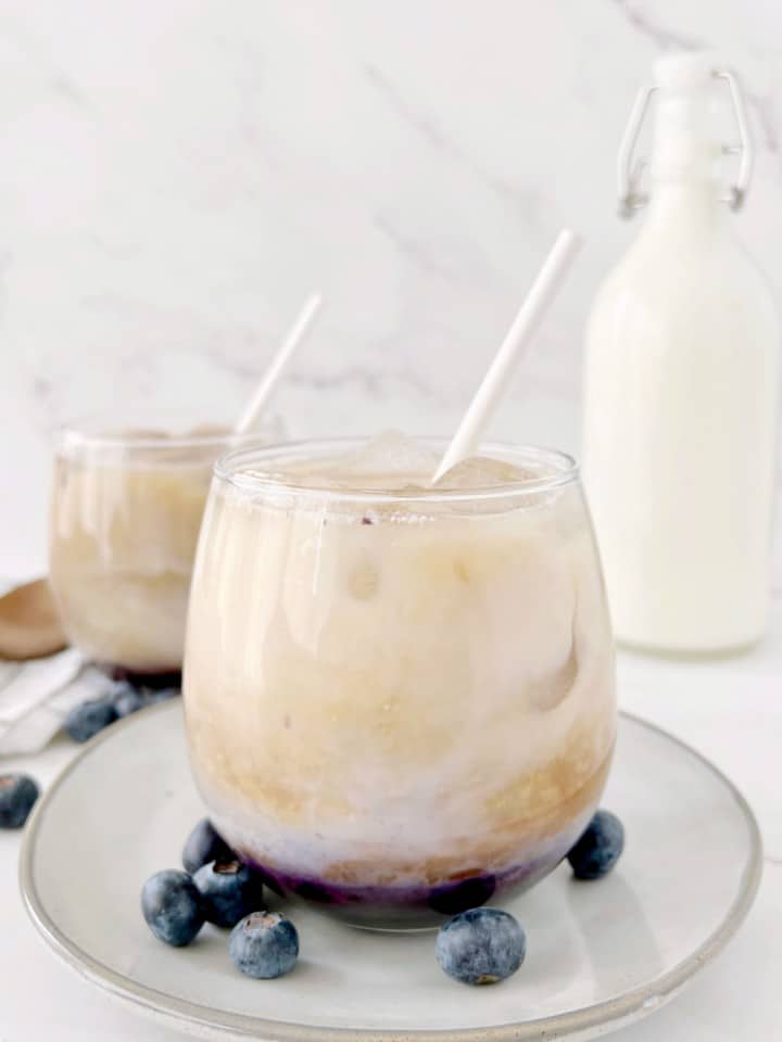 cups of blueberry lattes next to blueberry fruit