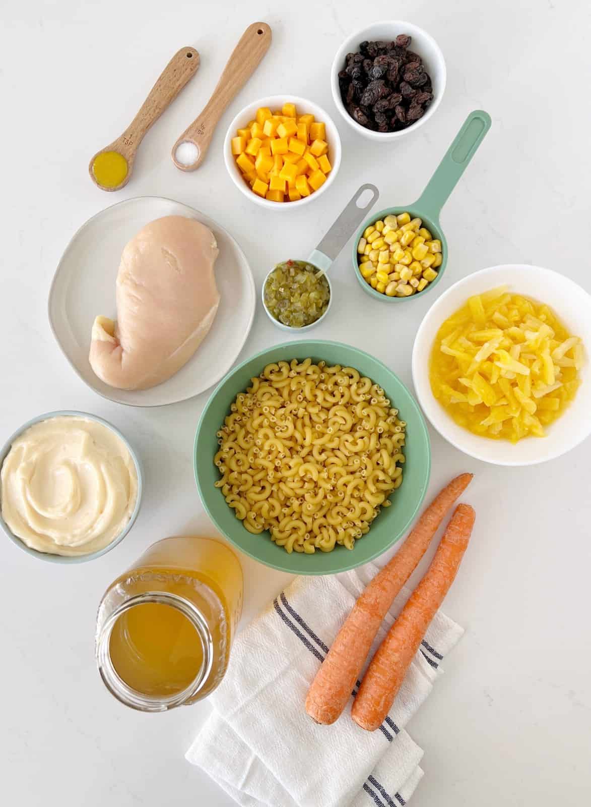 bowls of ingredients for macaroni salad, chicken macaroni, cheese, raisins, carrots, etc 