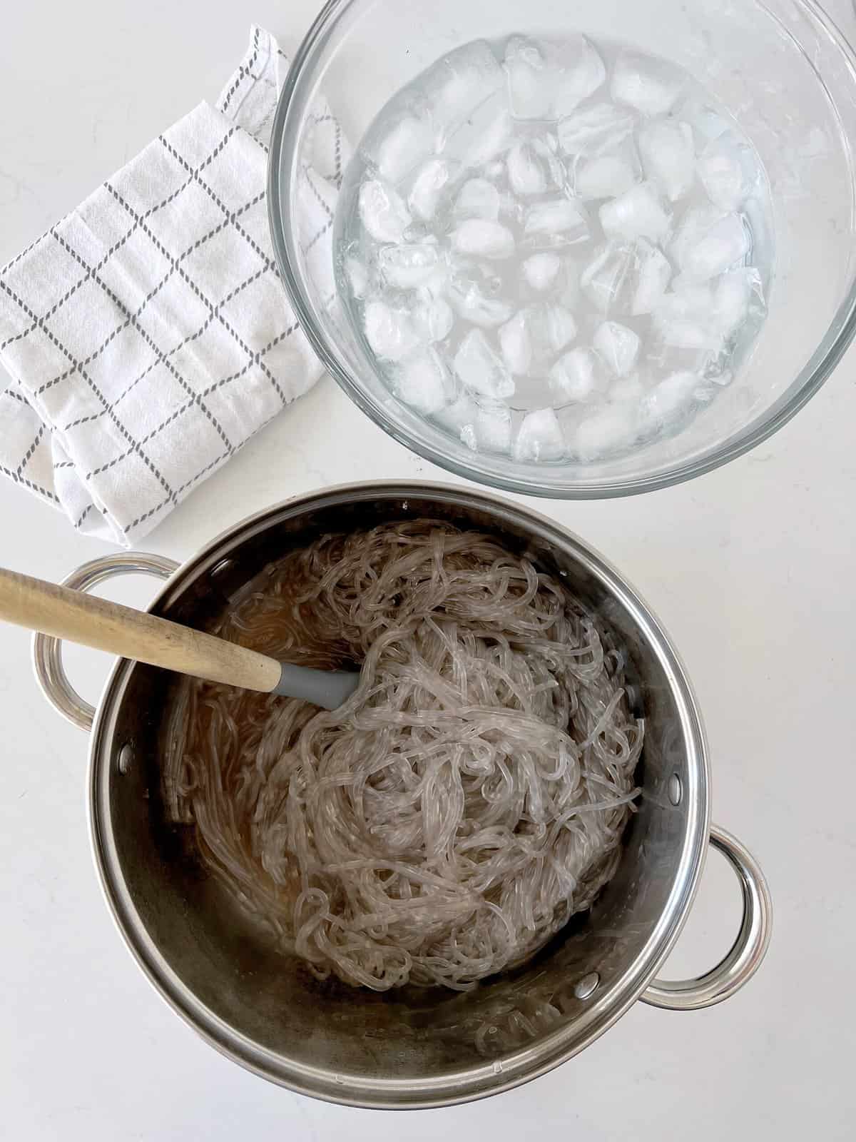 bowl of ice water next to cooked noodles 