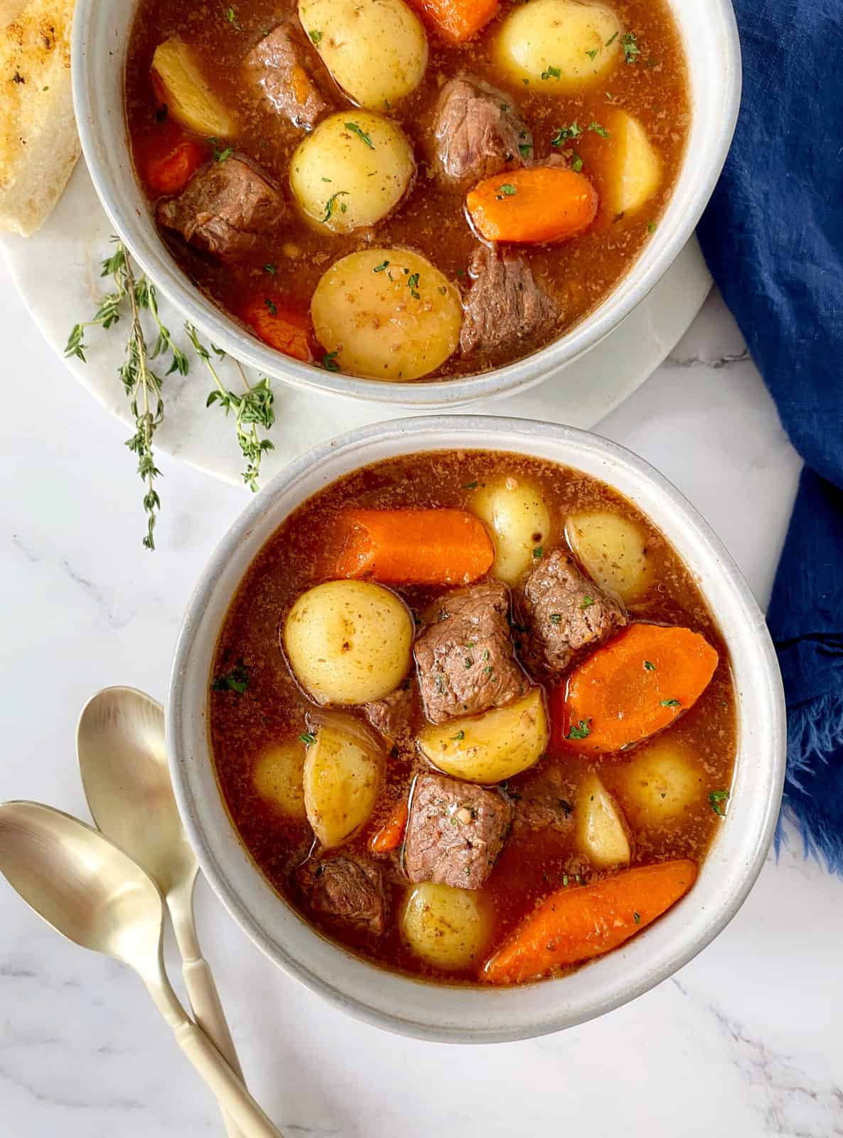 bowls of beef soup next to spoons 