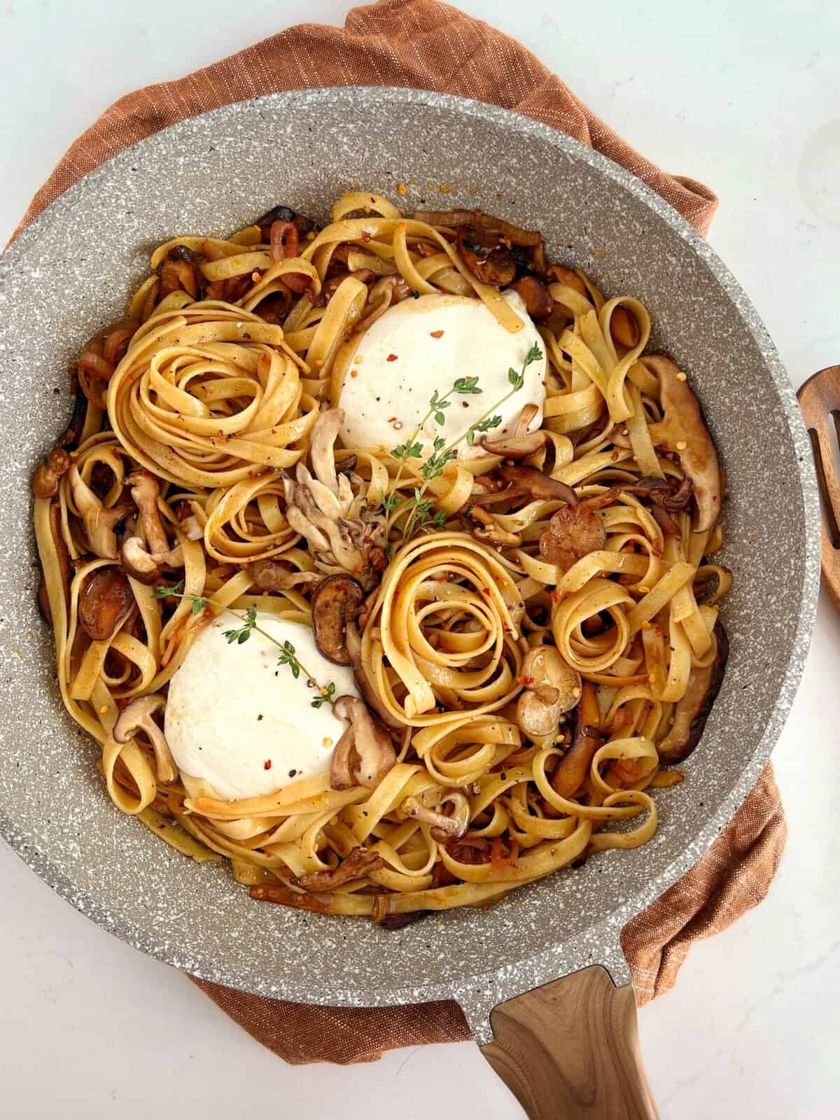burrata cheese in a pan of pasta and mushrooms 
