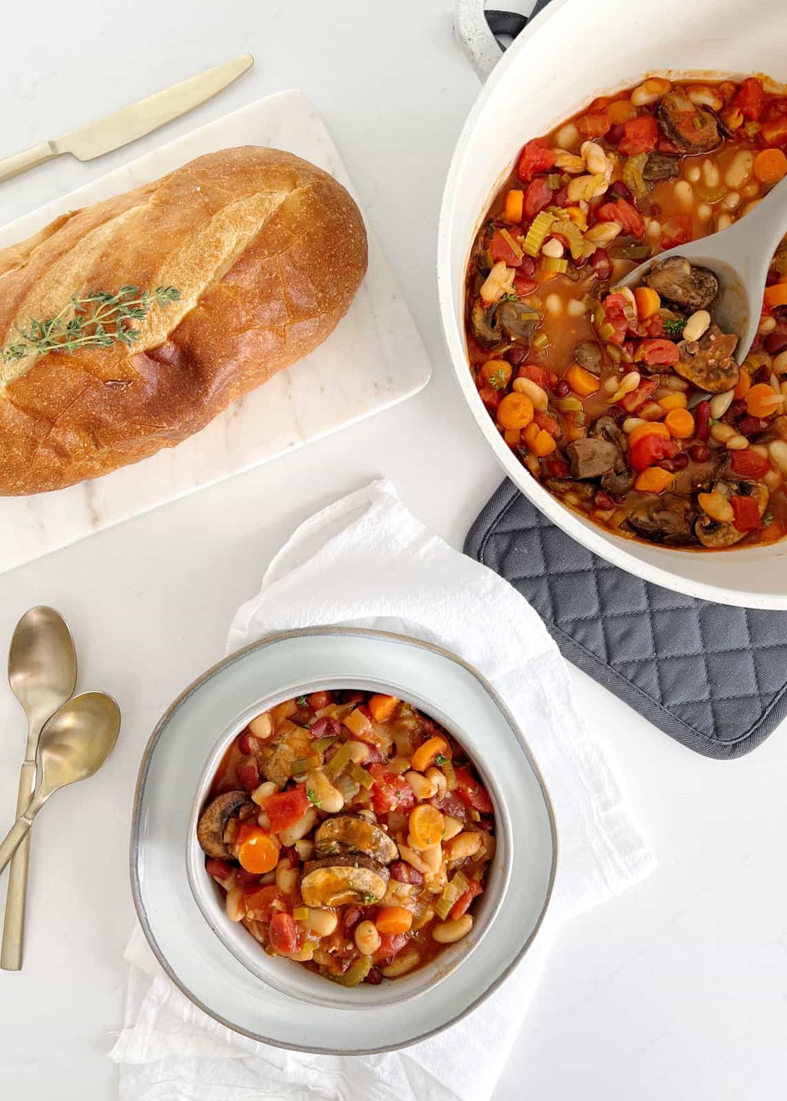 bowl of cassoulet next to a pot of cassoulet and bread 