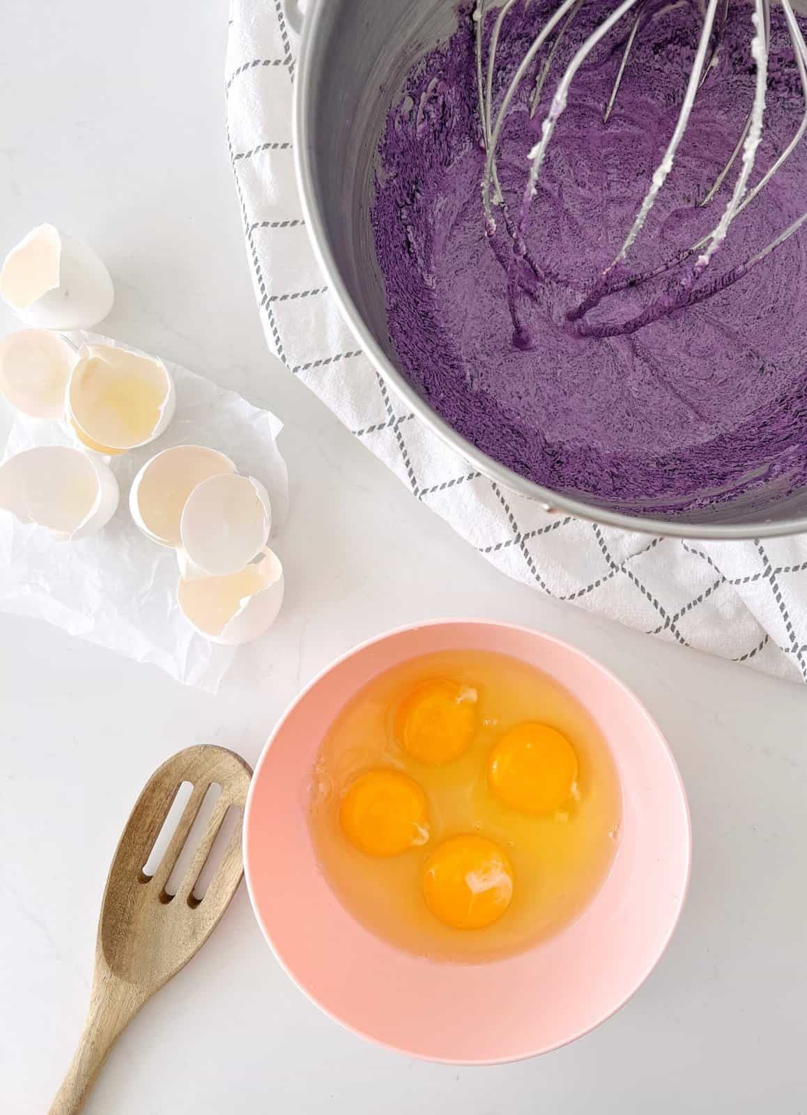 eggs in a bowl with mixing bowl of ube batter 