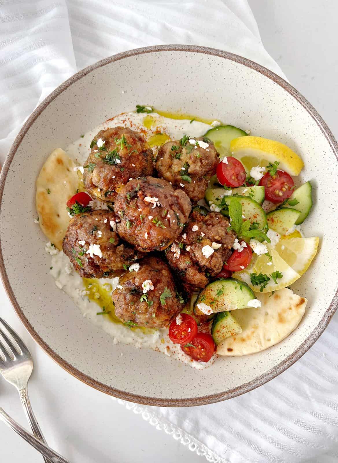greek meatballs on a plate with hummus and vegetables on a plate 