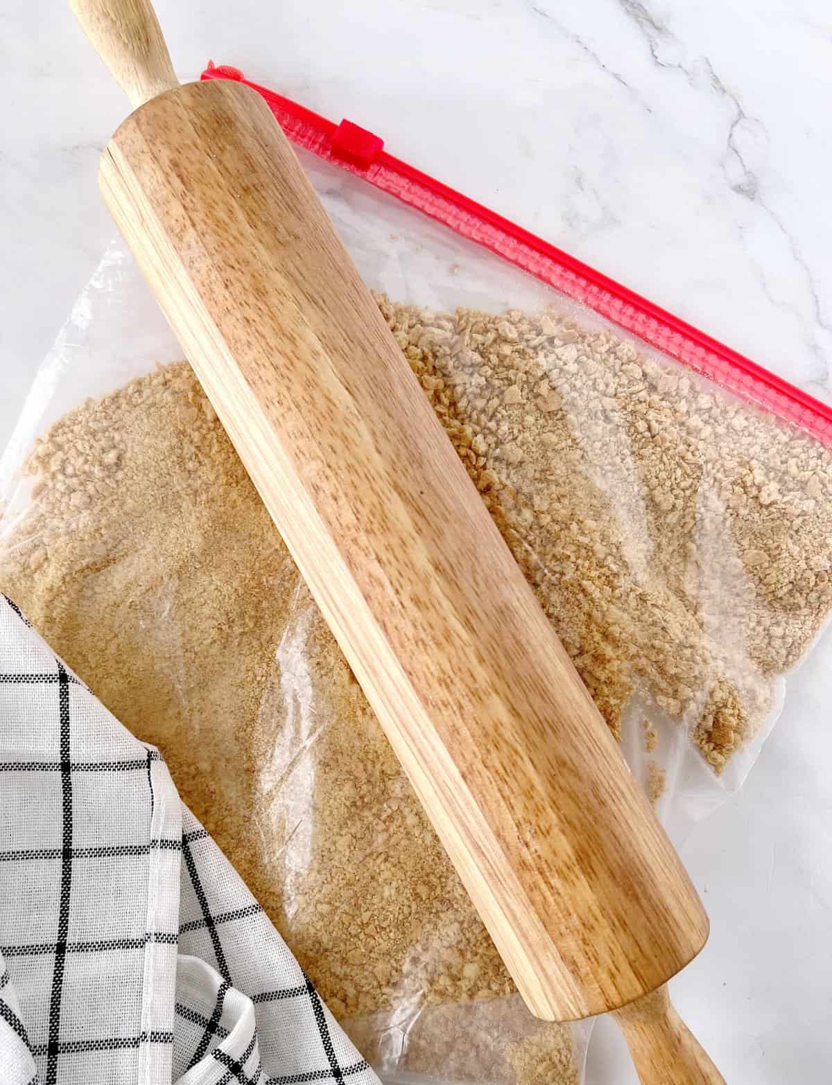 rolling pin with graham crackers in a ziplock bag