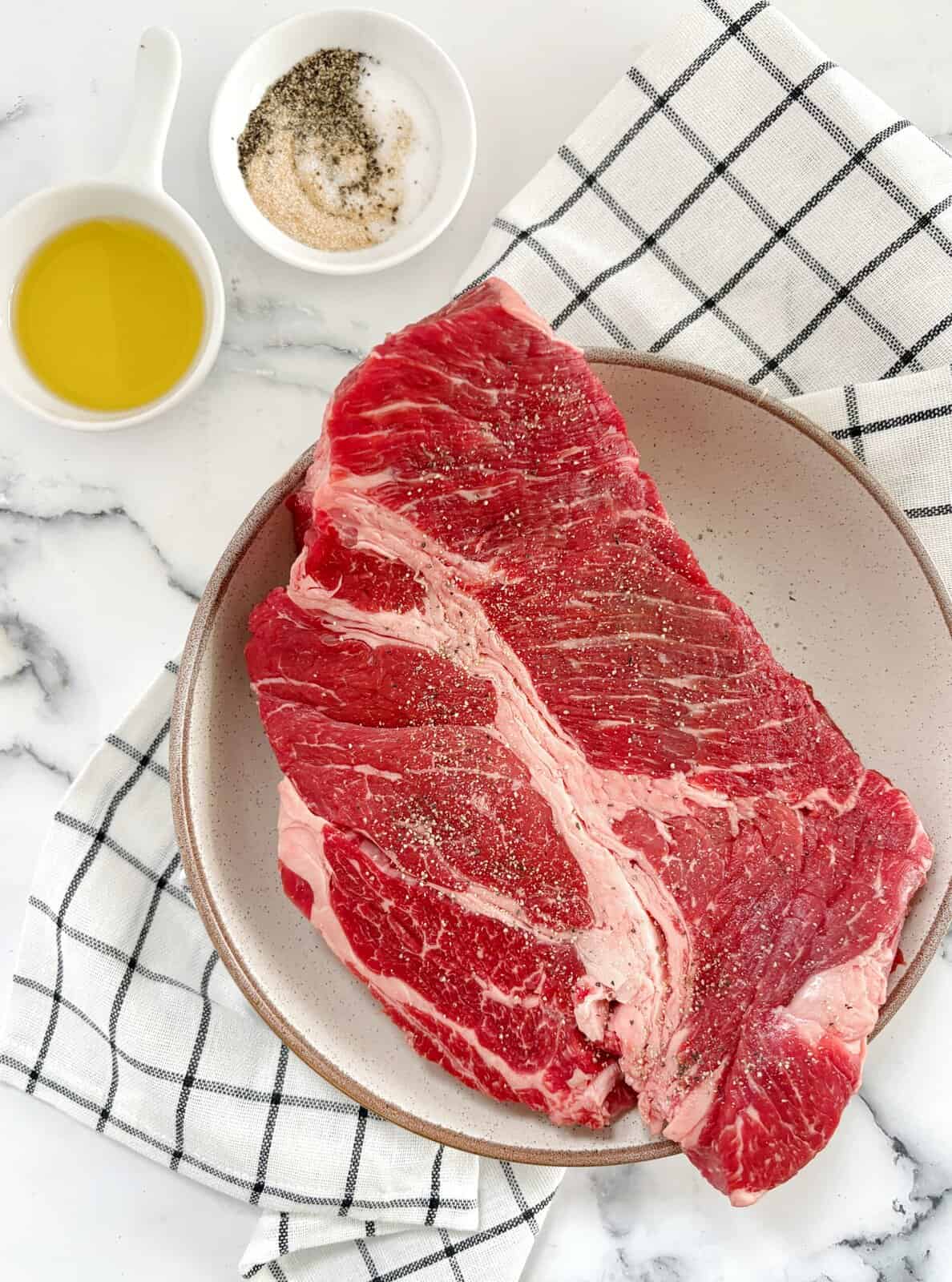 meat on a palte with seasonings on the side and on top of it