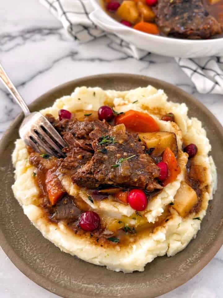 cranberry pot roast portion on a plate with mashed potatoes