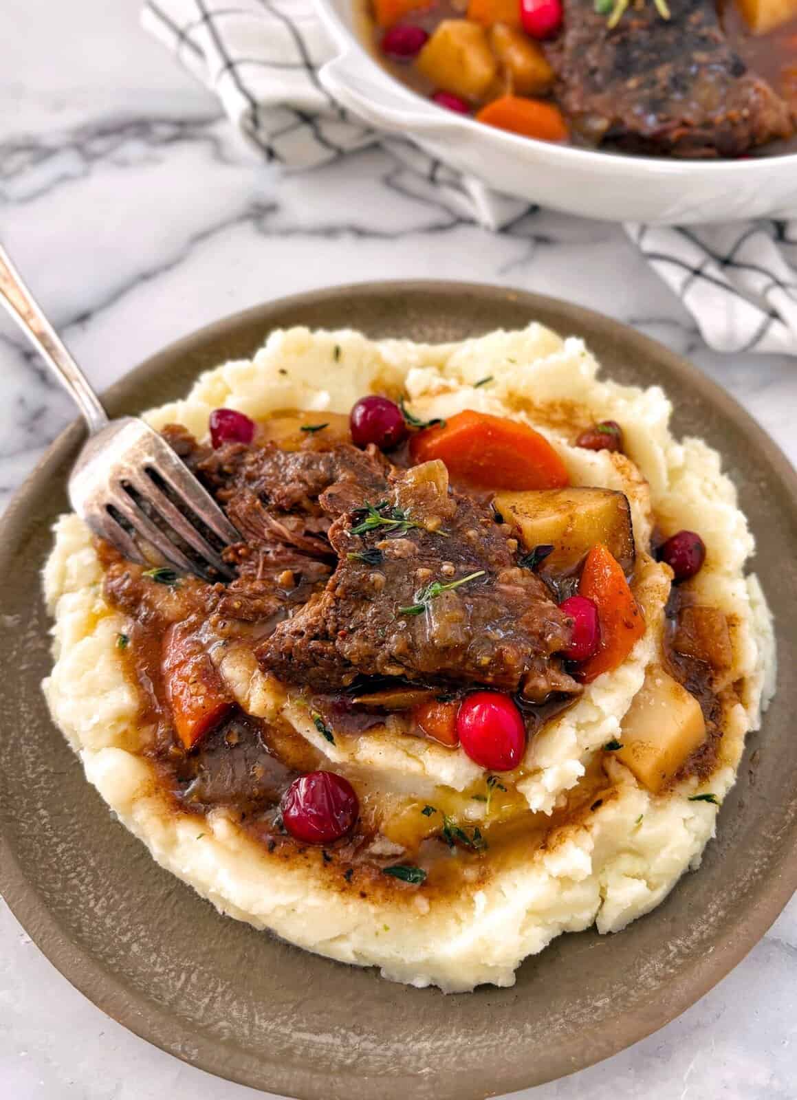 cranberry pot roast portion on a plate with mashed potatoes