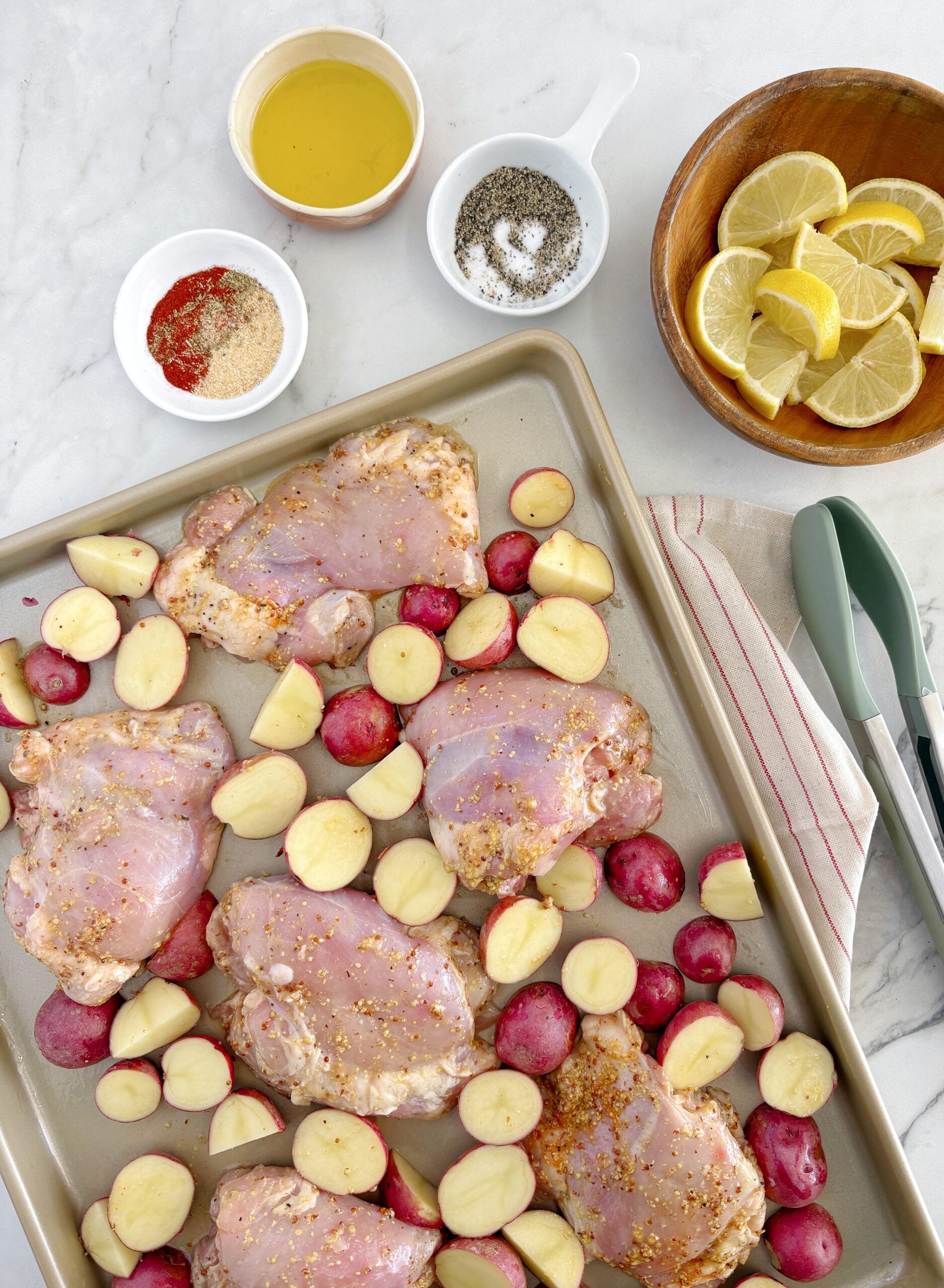 baking sheet with raw chicken and potatoes